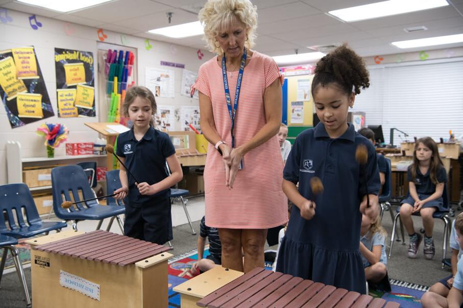 Elementary teacher with two students playing xylophones